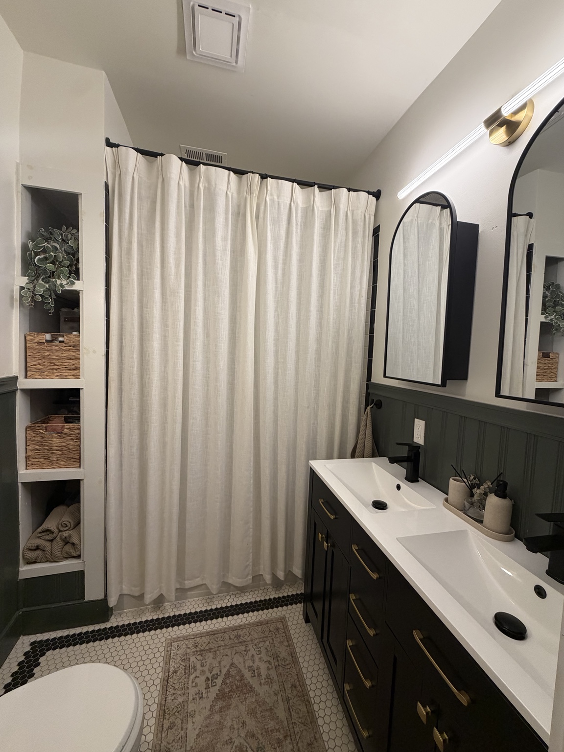 Two black arched medicine cabinets installed above the finished double vanity