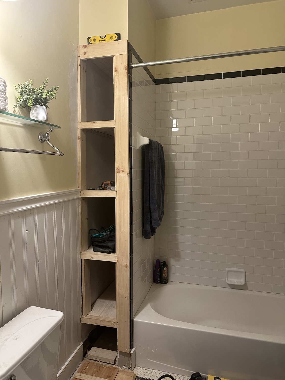 Tall built-in bathroom shelf framed beside the shower