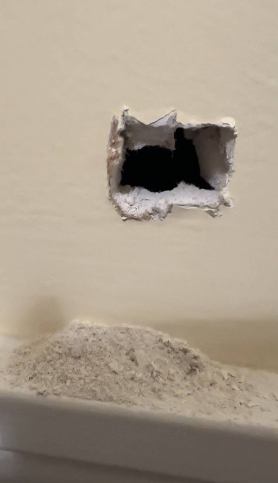 The first test hole cut into the hollow wall beside the upstairs shower