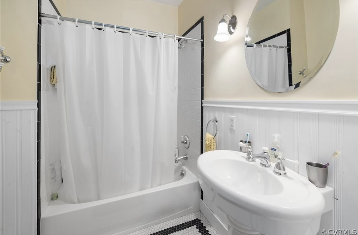 Upstairs bathroom before the updates with a pedestal sink, oval mirror, and yellow walls
