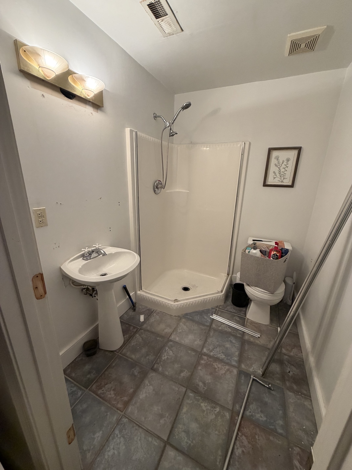 Wide view of the original bathroom with pedestal sink, fiberglass shower, and toilet