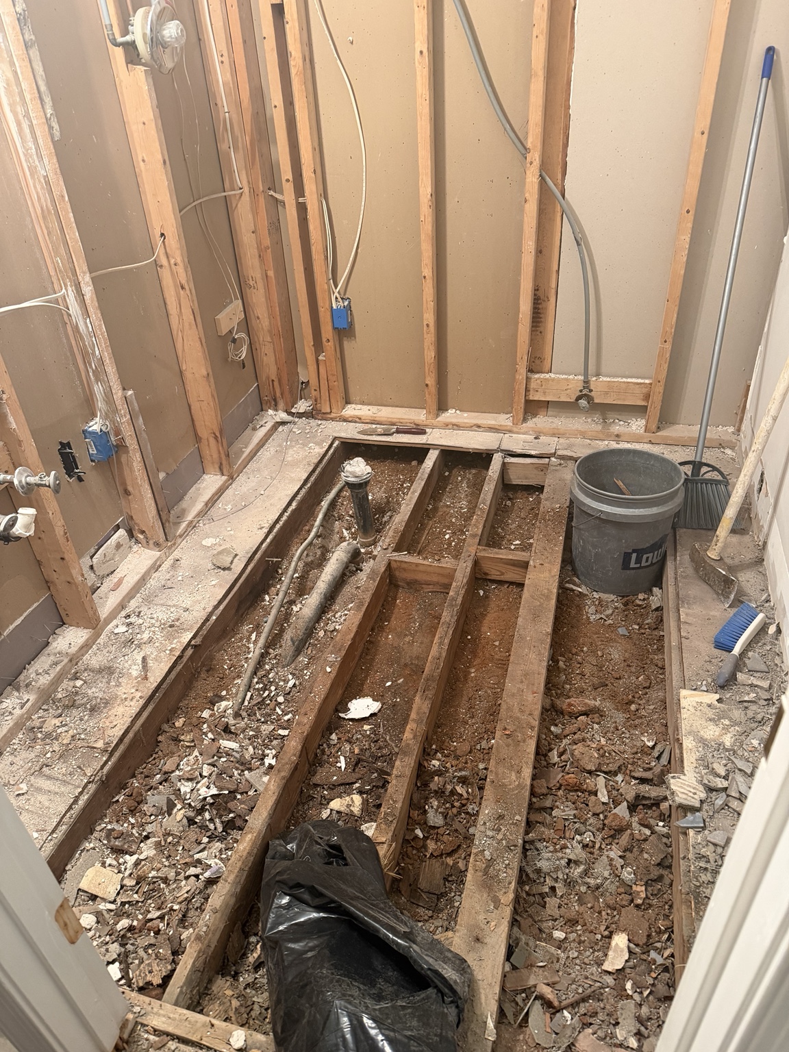 Bathroom floor removed to expose joists, plumbing, and Richmond red clay