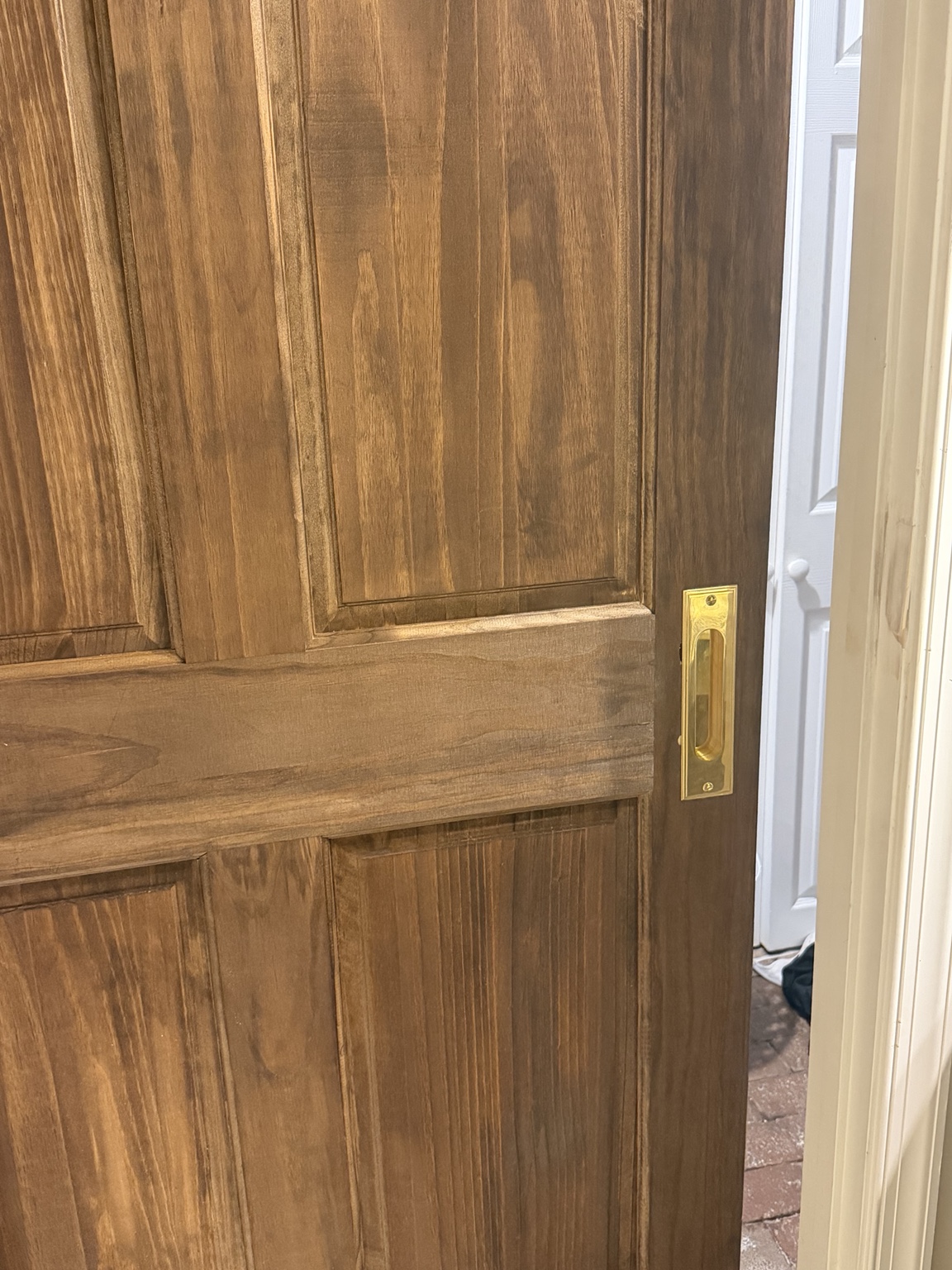 Stained solid-core bathroom door installed on a concealed sliding track
