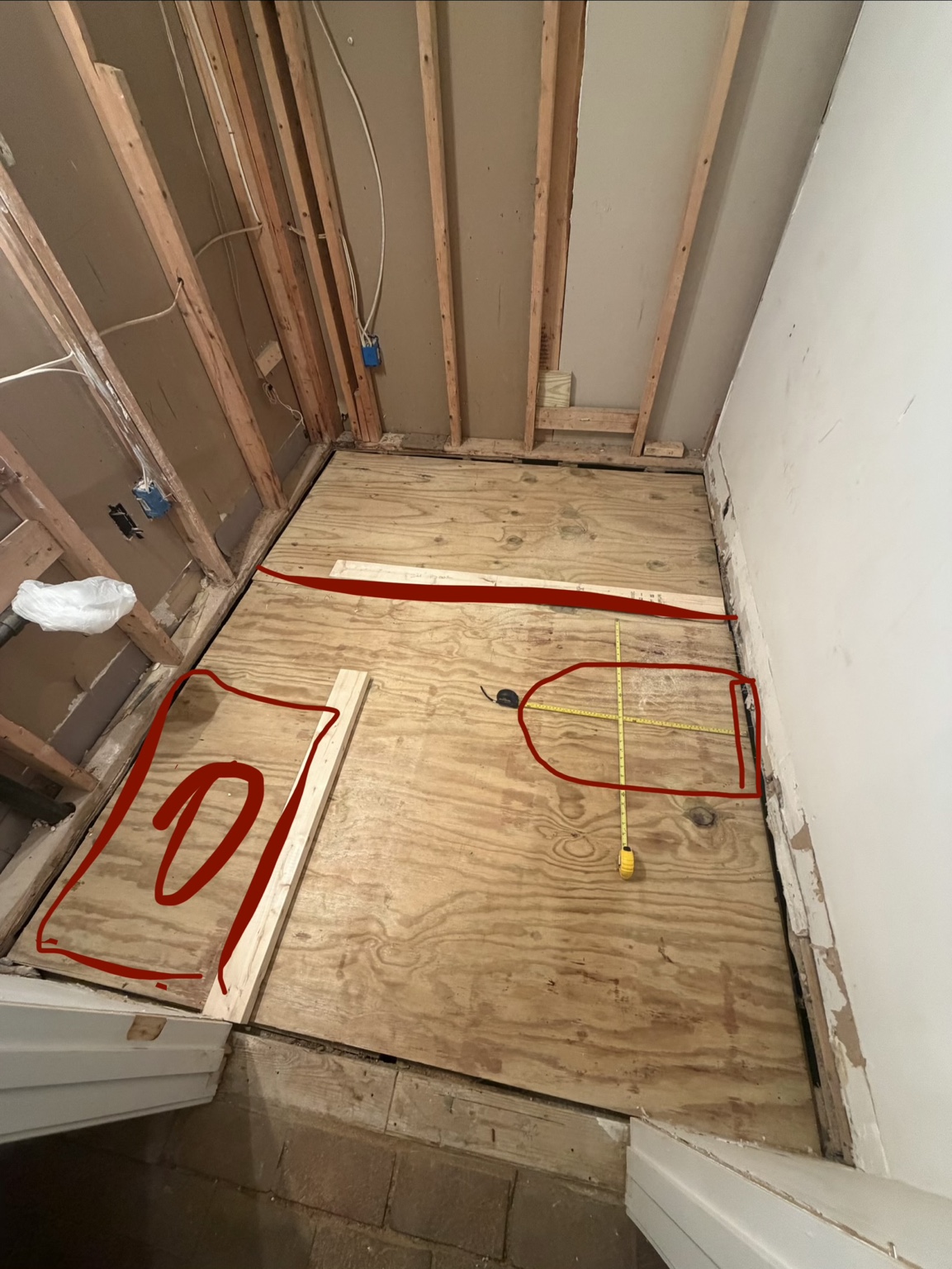 Bathroom layout marked in red on the plywood subfloor
