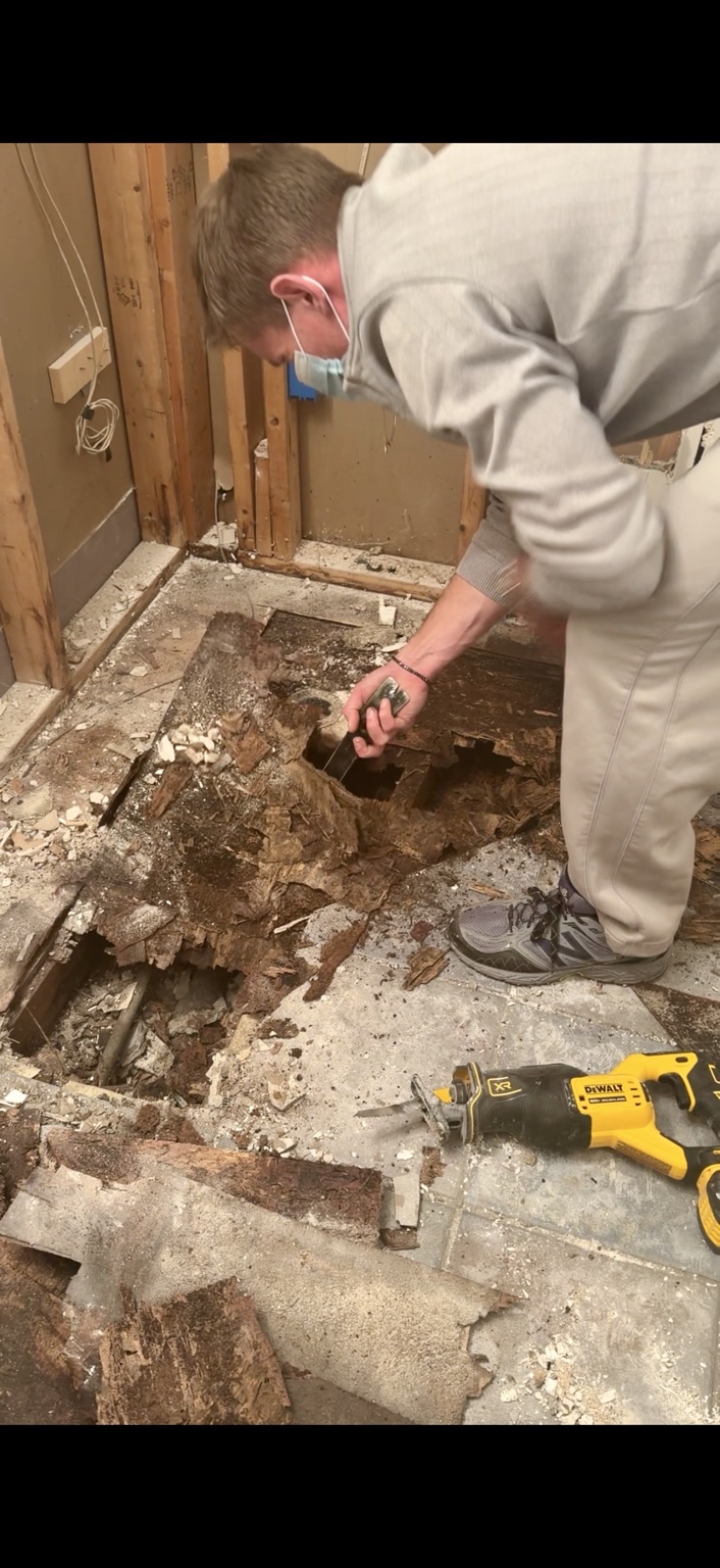Derrick examining the severely rotted bathroom floor during demolition