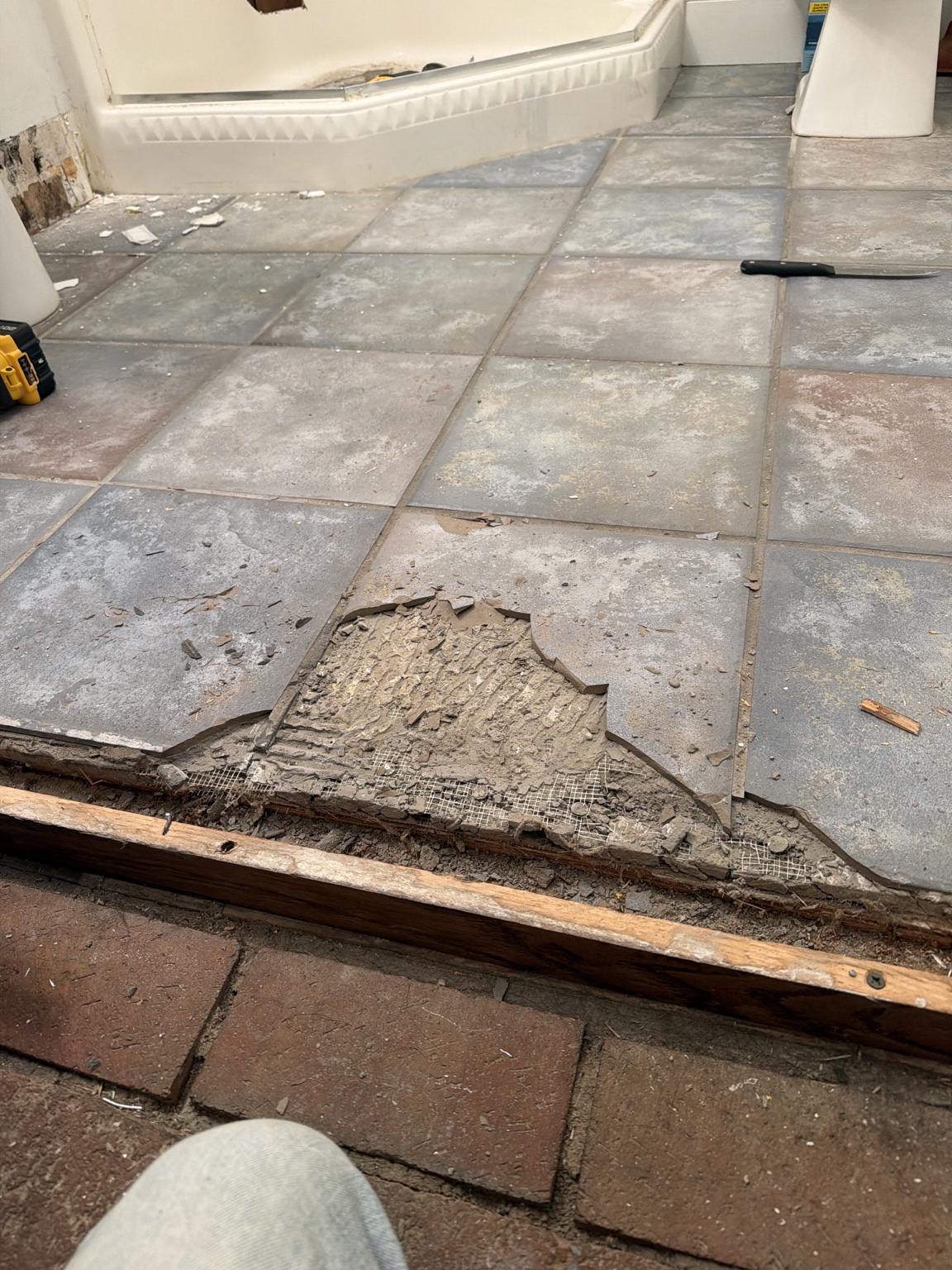 Original basement bathroom floor raised above the brick hallway