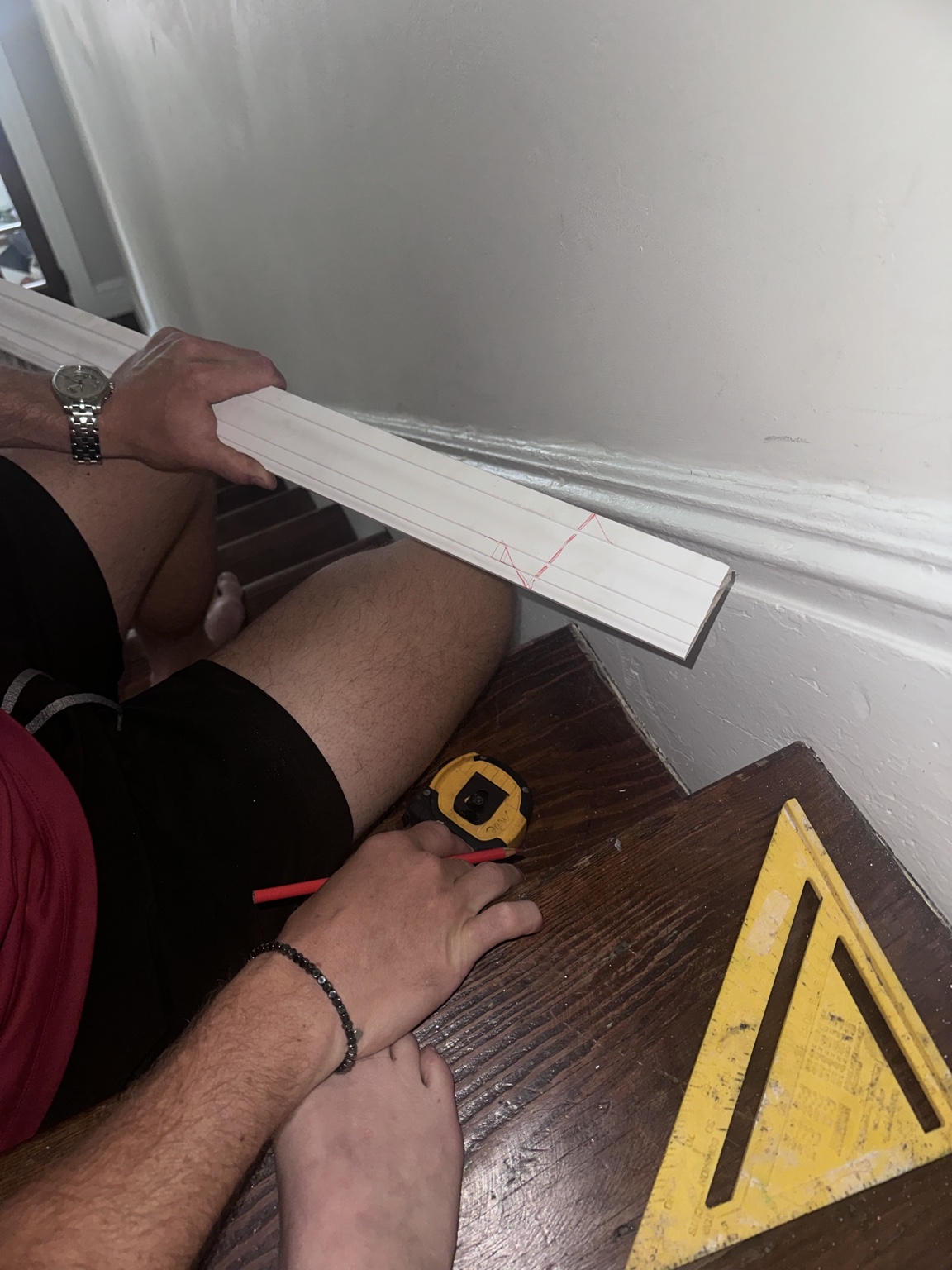 Patterned carpet runner being fitted to the uneven wooden staircase