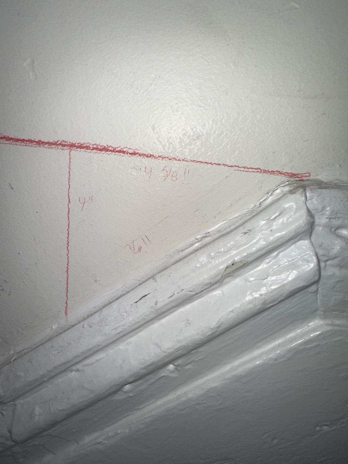 Pencil lines and measurements on the stairwell wall while calculating the changing molding angles