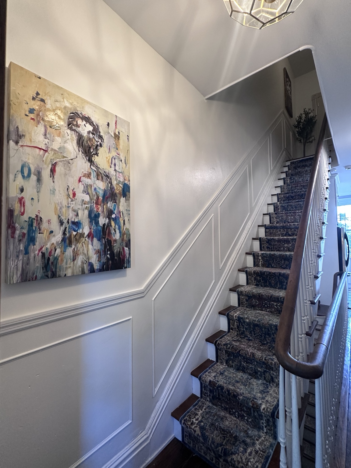 Finished staircase with picture frame molding and a patterned carpet runner