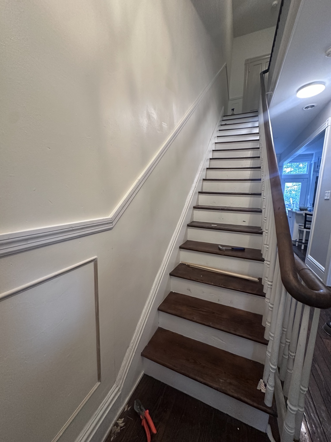 Picture frame molding being installed along the uneven staircase wall